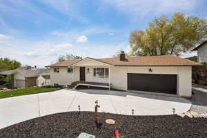Ranch-style home featuring driveway, a chimney, brick siding, an attached garage, and a shingled roof