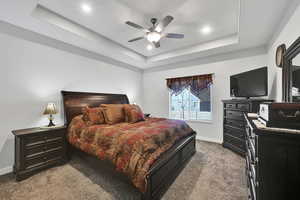 Carpeted bedroom with recessed lighting, a tray ceiling, baseboards, and a ceiling fan