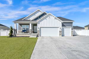 View of front of house with a front lawn, a gate, fence, board and batten siding, and an attached garage