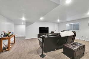 Cinema room with visible vents, light carpet, and baseboards