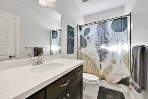 Bathroom featuring vanity, tile patterned floors, shower / bath combination with curtain, and toilet