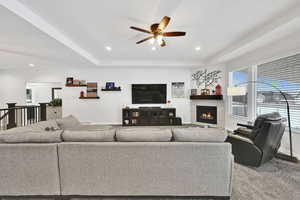 Living room with recessed lighting, a fireplace, a raised ceiling, and baseboards