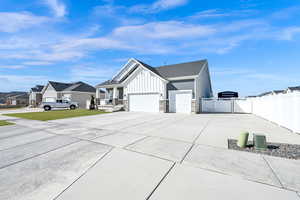 View of home's exterior featuring a gate, fence, board and batten siding, concrete driveway, and an attached garage