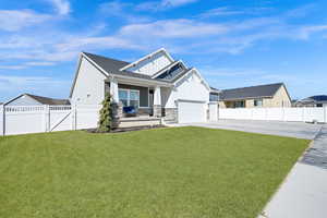 View of front of house featuring board and batten siding, a front lawn, fence, concrete driveway, and a gate