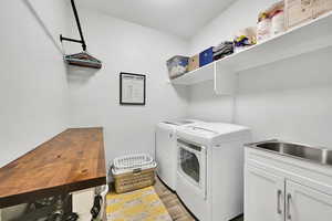 Washroom with cabinet space, light wood-style flooring, and separate washer and dryer