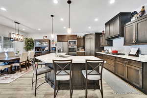 Kitchen featuring stainless steel fridge with ice dispenser, built in microwave, light countertops, decorative backsplash, and a sink