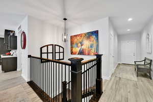 Hall featuring visible vents, an upstairs landing, recessed lighting, light wood-style floors, and baseboards