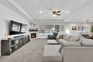 Living room featuring recessed lighting, a tray ceiling, carpet flooring, and a tile fireplace