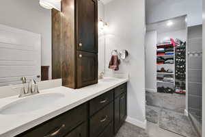 Bathroom with a sink, a walk in closet, baseboards, and double vanity