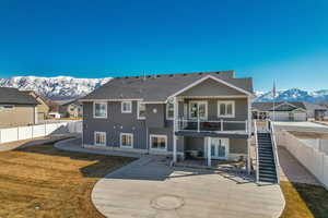 Rear view of house with stairway, a large concrete patio area, a mountain view, and a fenced backyard