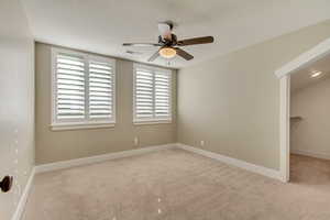 Upstairs bedroom (3) featuring  a walk in closet, carpet, baseboards, and ceiling fan.