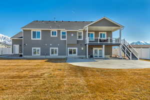 Rear view of property with fence, a yard, stucco siding, french doors, and a large patio area.