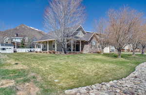 View of front of home featuring a mountain view, covered porch, a front yard, and fence