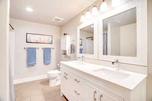 Bathroom with a sink, visible vents, toilet, and tile patterned flooring