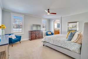 Bedroom with crown molding, ceiling fan, baseboards, carpet floors, and arched walkways