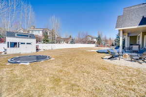 View of yard featuring a fenced backyard, an outdoor fire pit, an outdoor structure, and a trampoline