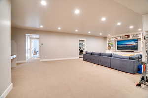 Living room with built in shelves, recessed lighting, light colored carpet, and baseboards