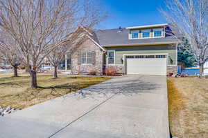 View of front of house with a garage, stone siding, concrete driveway, and a front lawn