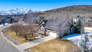 Exterior space featuring driveway, stone siding, a mountain view, a residential view, and an attached garage