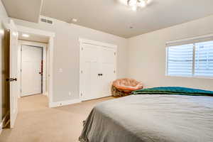 Bedroom featuring baseboards, visible vents, a closet, and light carpet