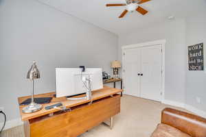 Home office with baseboards, light carpet, and a ceiling fan