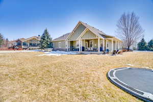 View of front of house featuring a front yard, a patio area, board and batten siding, and an outdoor fire pit