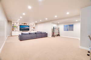 Living room with built in features, recessed lighting, baseboards, and light carpet