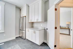 Kitchen featuring white cabinetry, light countertops, stainless steel refrigerator with ice dispenser, and a wealth of natural light