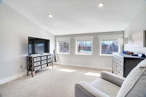 Living area featuring recessed lighting, baseboards, lofted ceiling, and light carpet