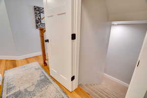 Stairway with wood finished floors and baseboards