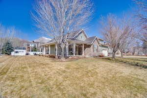 View of front of house with brick siding, a porch, an attached garage, and a front lawn