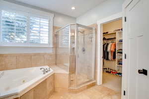 Full bathroom with a spacious closet, a jetted tub, and a shower stall