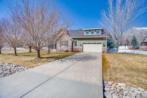 View of front of property with stone siding, driveway, and a front lawn