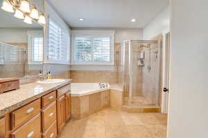 Full bath featuring recessed lighting, a stall shower, vanity, and a garden tub