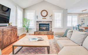 Living area featuring a fireplace, lofted ceiling, plenty of natural light, and wood finished floors