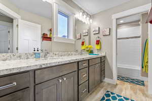 Bathroom featuring a sink, baseboards, wood finished floors, and double vanity