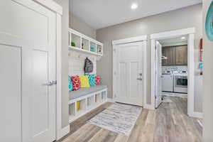 Mudroom featuring recessed lighting, light wood-type flooring, baseboards, and washer and clothes dryer