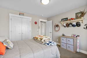 Carpeted bedroom with a closet and baseboards