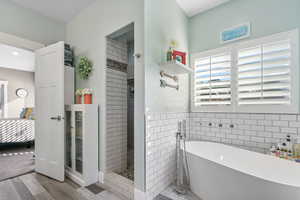 Master Bathroom with tile walls, a freestanding tub, wood finished floors, and walk in shower