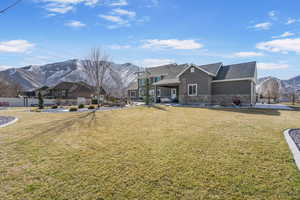 Rear view of house featuring stucco siding, a lawn, a mountain view, and fence