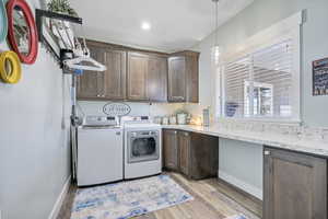 Clothes washing area featuring washer and dryer, baseboards, cabinet space, and light wood-style flooring