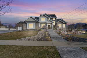 Craftsman-style home featuring a front lawn, stone siding, a garage, and driveway