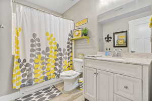 Bathroom with visible vents, toilet, vanity, and shower / tub combo with curtain