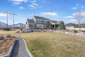 Back of property with stone siding, a lawn, a mountain view, and fence