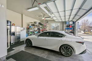 Garage with stainless steel fridge and a garage door opener