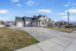 View of front of home with a mountain view, driveway, a front lawn, and an attached garage