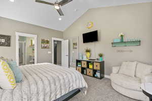 Carpeted bedroom featuring vaulted ceiling, a ceiling fan, baseboards, and connected bathroom