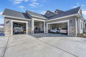 View of side of property featuring stucco siding, stone siding, concrete driveway, an attached garage, and a shingled roof