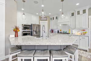 Kitchen featuring a sink, stainless steel appliances, backsplash, and white cabinetry