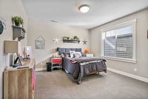 Carpeted bedroom featuring visible vents, baseboards, and a textured ceiling